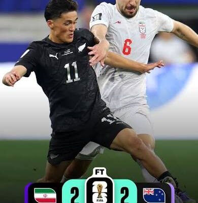 New Zealand player number 11 and Iran player number 6 battling for the ball in a 2-2 draw at FIFA World Cup 2026 match scoreline shown at bottom
