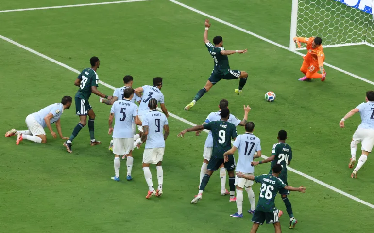 Saudi Arabia and Uruguay players crowding the penalty box during a goal-mouth scramble at FIFA World Cup 2026, with goalkeeper diving to make a save